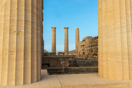 View through majestic ancient stone pillars of the acropolis of lindos on a hot summer day.の写真素材