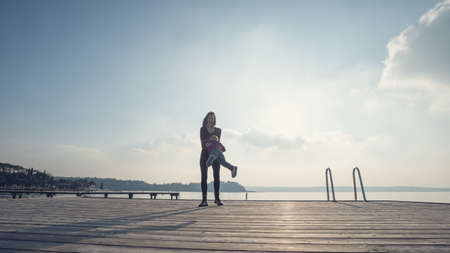 Happy young mother standing on wooden pier above the sea spinning her toddler son as they enjoy their time together.の写真素材