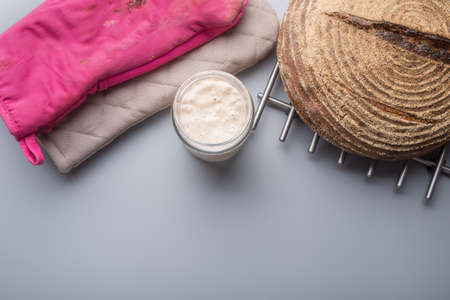 Top view of sourdough starter yeast in a jar next to a freshly baked home made bread.の写真素材
