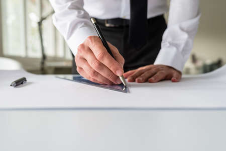 Architect or designer drawing a draft on a paper using a pencil and a ruler.の写真素材