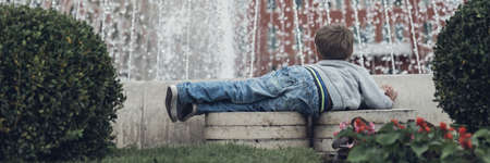 Wide view image of toddler boy lying in front of a water fountain in city of Split.の写真素材