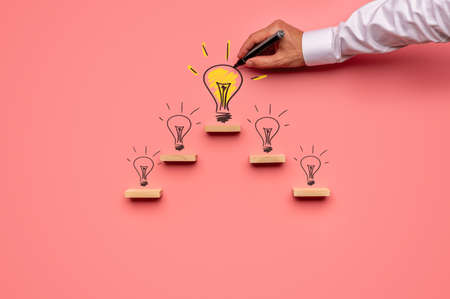Business vision and idea concept - businessman drawing light bulbs on pink background.