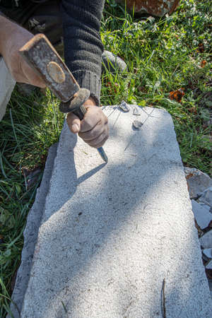 Top view of an artist carving in stone using mallet and a chisel.
