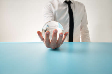 Front view of a man in elegant shirt and tie holding crystal sphere in
his hand in front of him in a conceptual image.の写真素材