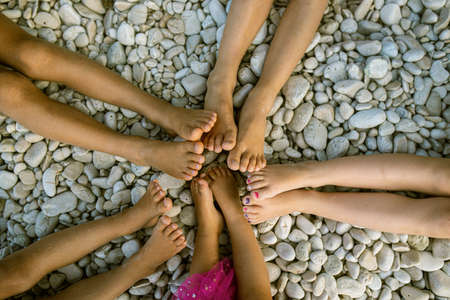 Top view of feet of five kids in a star shape on pebble beach.の写真素材