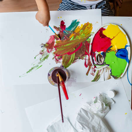 Top view of a toddler child painting with colors and brushes.の写真素材