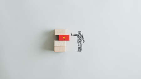 Conceptual image of business idea and vision with silhouette of a man pushing a red wooden peg with lightbulb in to a stack of pegs. Over grey background.の写真素材
