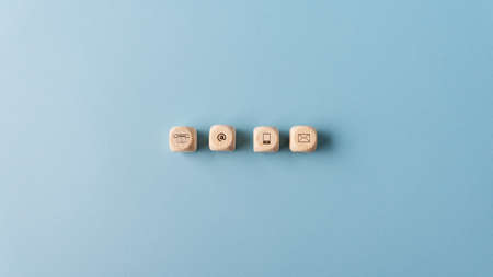 Contact and communication icons on wooden dices placed in a row. Over blue background.の写真素材