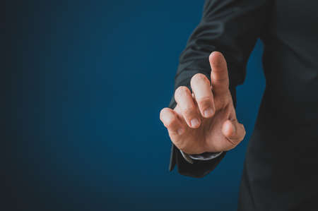 Businessman touching blank virtual screen with his finger. Over navy blue background with copy...