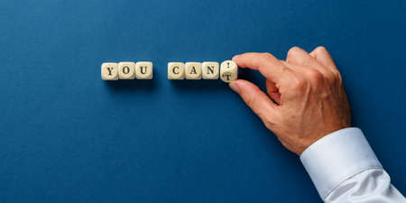 You cant sign on wooden dices with male hand flipping the last dice to change it into a You can! sign. Over navy blue background.の写真素材