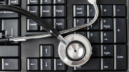 Top view of stethoscope on black computer keyboard in a conceptual image.