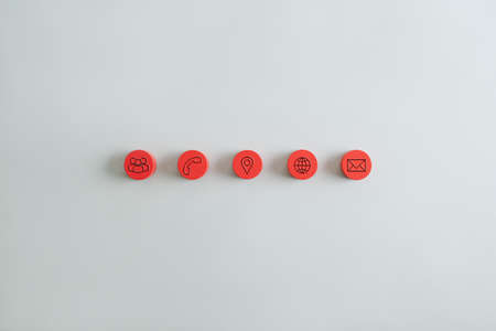Five red round wooden pieces in a row with contact and information icons on them.の写真素材