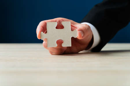 Businessman holding blank puzzle piece showing it to the camera.の写真素材