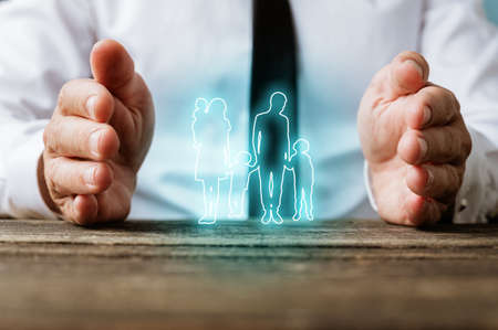 Glowing silhouette of a family on virtual interface with male hands making protective gesture around it in a conceptual image.の写真素材