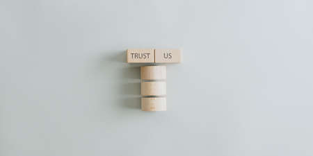 Trust us sign on pillar made of wooden circles and blocks in a conceptual image. Over beige background.の写真素材