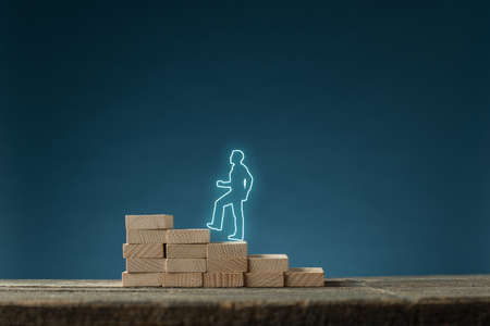 Glowing sihouette of businessman walking up the stairs made of wooden pegs in a conceptual image....
