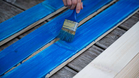 Male hand painting wooden planks with a brush with blue color.の写真素材
