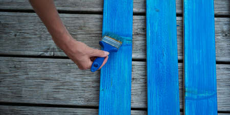 Top view of female hand painting wooden plank with blue color.の写真素材