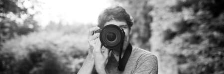 Wide view monochrome image of male photographer taking photo at you standing outside in nature.の写真素材
