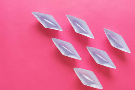 Six paper origami made boats on pink background in a conceptual image. With copy space.