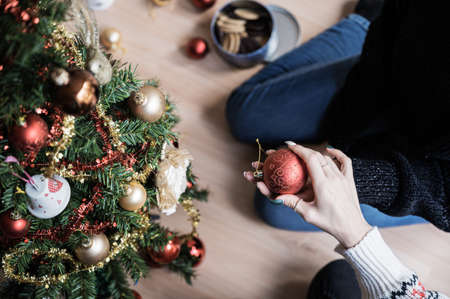 Top view of two girlfriends decorating Christmas tree together one passing red holiday bauble to the other.の写真素材