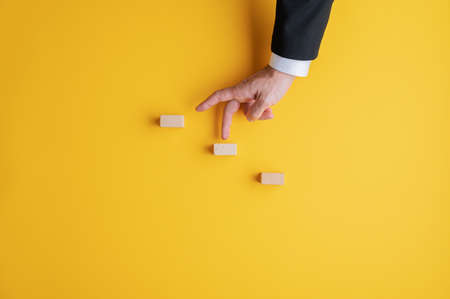 Businessman walking his fingers up the metaphorical steps. Over yellow background with copy space.