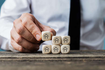Front view of real estate agent stacking wooden dices with house symbols on them in a conceptual...