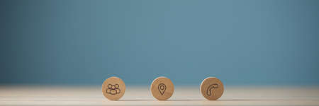Wide view image of three wooden cut circles with contact and information icons on them placed in a row. Over blue background with copy space.の写真素材