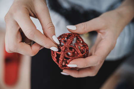 Top view of a woman attaching golden string to red Christmas ornament.の写真素材