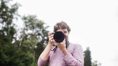Young man taking a photo with dslr camera directly at you. の写真素材
