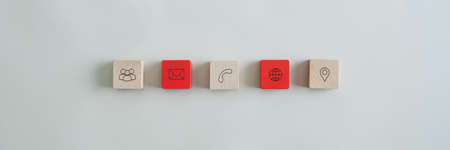 Wide view image of five wooden blocks with contact and information icons placed over grey background.の写真素材