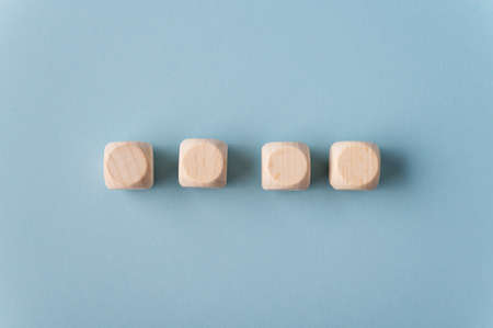 Four blank wooden dices placed in a row over light blue background.