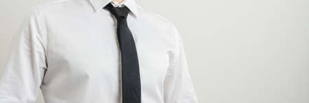 Wide view image of a businessman torso in white shirt and black tie. With copy space to the right...