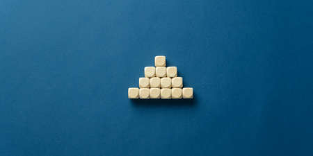 Pyramid build of blank wooden cubes over blue background. With plenty of copy space.の写真素材
