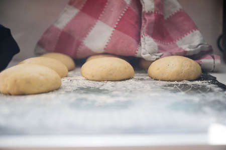 View under a cotton kitchen cloth of a rising home made bread buns or doughnuts.の写真素材