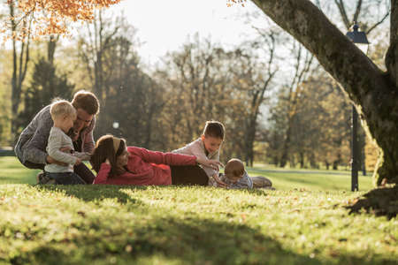 Happy young family with three children playing in an autumn  park.の写真素材