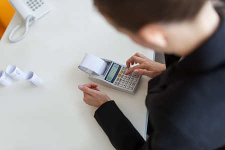 Overhead view of businesswoman accountant using calculator working at her desk.