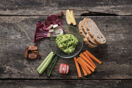 Top view of delicious vegan snack of carrots, cucumber, bread, tofu and pecan nuts arranged around...