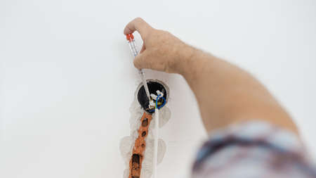 Closeup of electrician checking presence of electrical current in a wire coming from a wall.