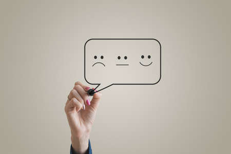 Customer feedback conceptual image with smiling, sad and neutral face symbol drawn in speech bubble.