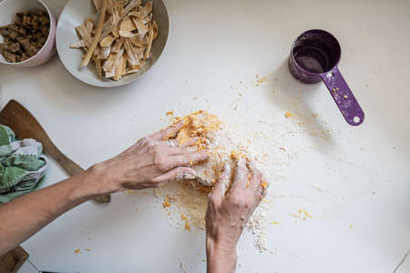 Top view of a woman kneading home made vegan dough for fresh pasta on kitchen counter.