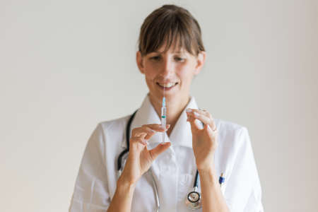 Young female doctor holding an injection flicking it before injecting.