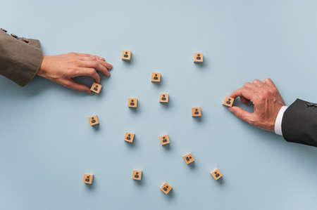 Human resources and employment conceptual image - male and female hands arranging wooden blocks with people icon on them.の写真素材