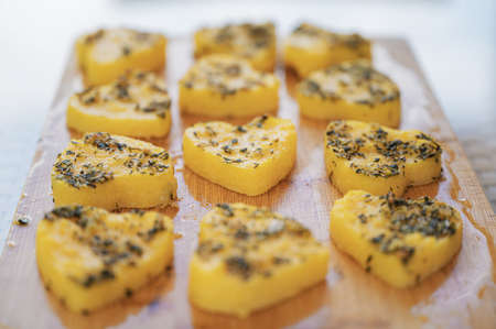 Closeup view of delicious polenta with herbs cut in heart shape.
