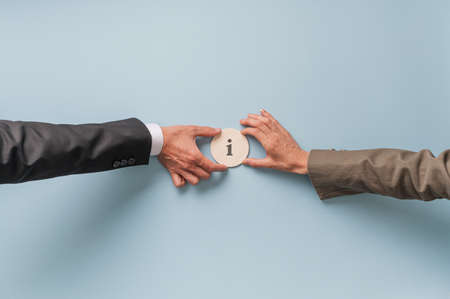 Businessman and businesswoman holding a wooden cut circle with an i letter on it in a conceptual...