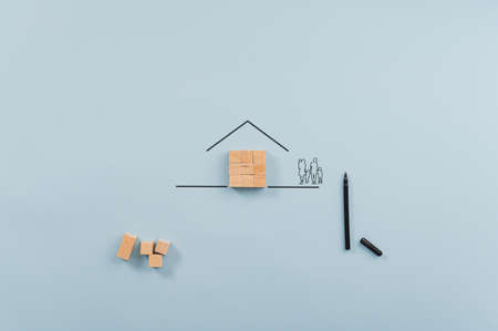 Hand drawn silhouette of a family next to a house made of wooden blocks in a conceptual image of home ownership and insurance.の写真素材