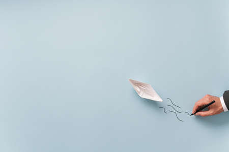 Hand of a businessman drawing waves behind a paper made origami boat in a conceptual image of business vision and goal.の写真素材