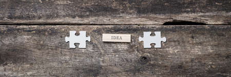 Wide view image of word Idea written on wooden peg in between two blank puzzle pieces. Conceptual of innovation and idea.の写真素材