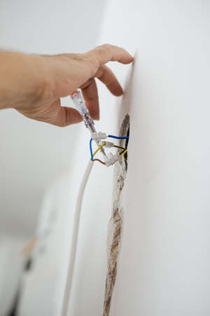 Low angle view of electrician checking wire  for presence of  electric current.の写真素材