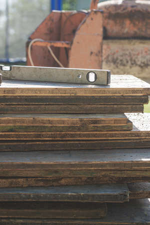 Builders level on a pile of wooden planks in an outdoor patio overlooking the garden in a construction and building concept.の写真素材